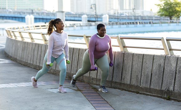 Two people exercising and doing lunges in the park.
