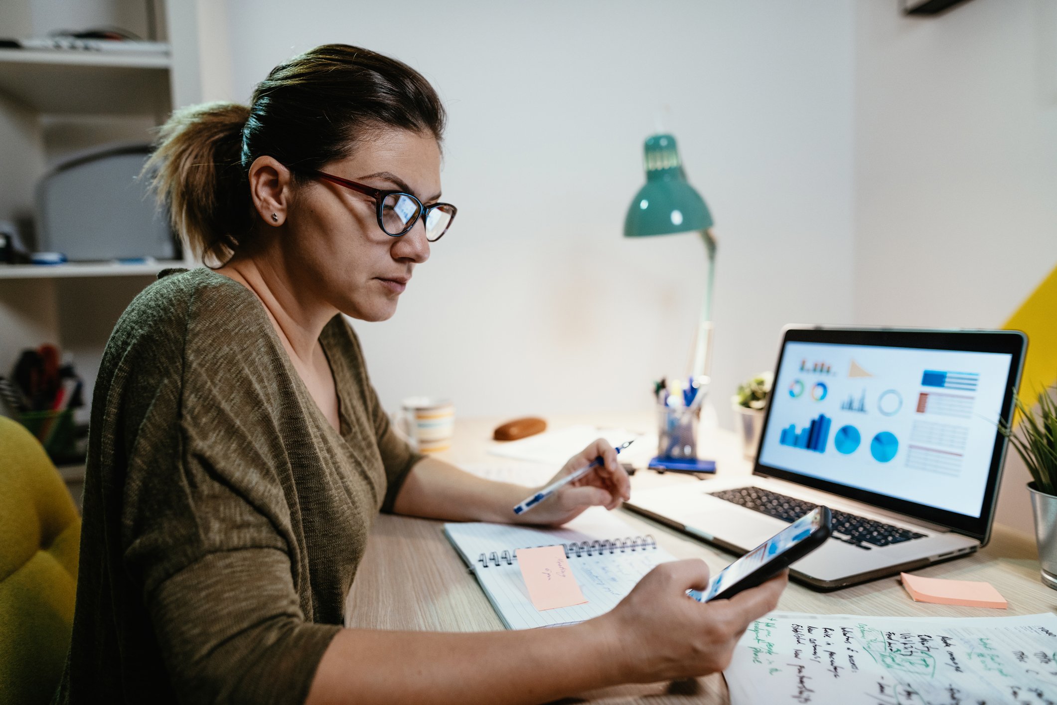 A person checks a stock portfolio on a laptop and a phone.