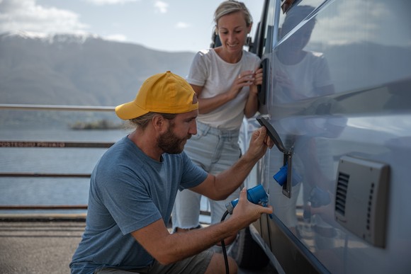 A couple hook up camper to electric outlet.