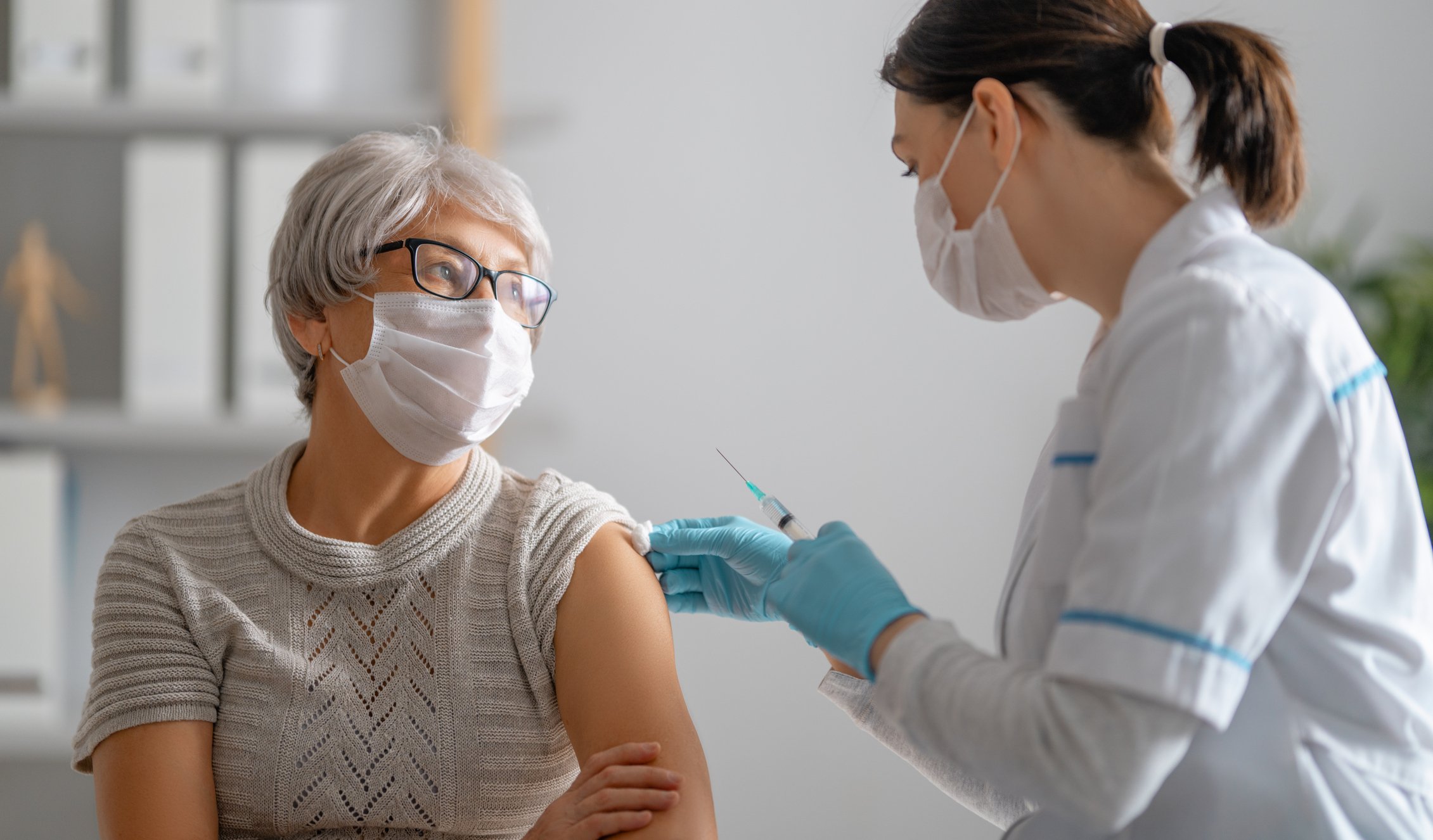 A healthcare worker prepares to vaccinate an individual.