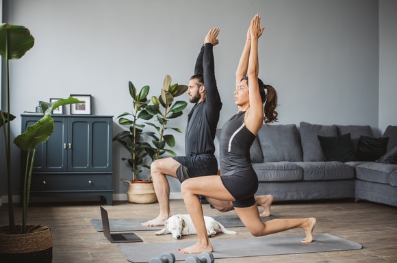 Two people practicing yoga at home.