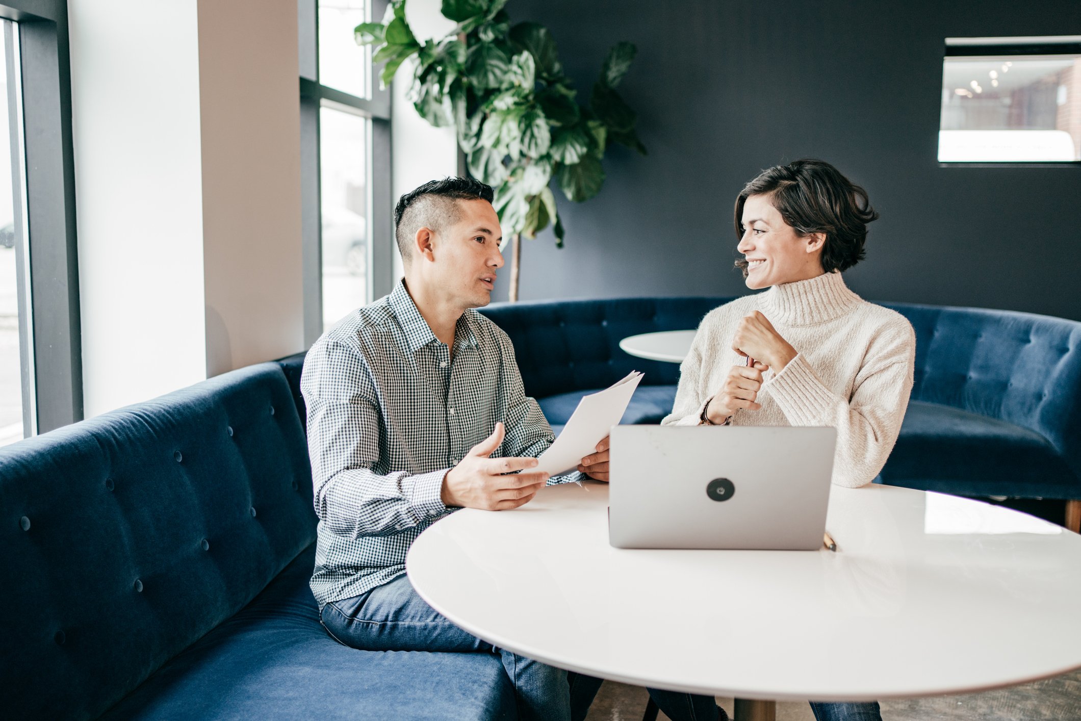Two professionals working at a laptop computer.