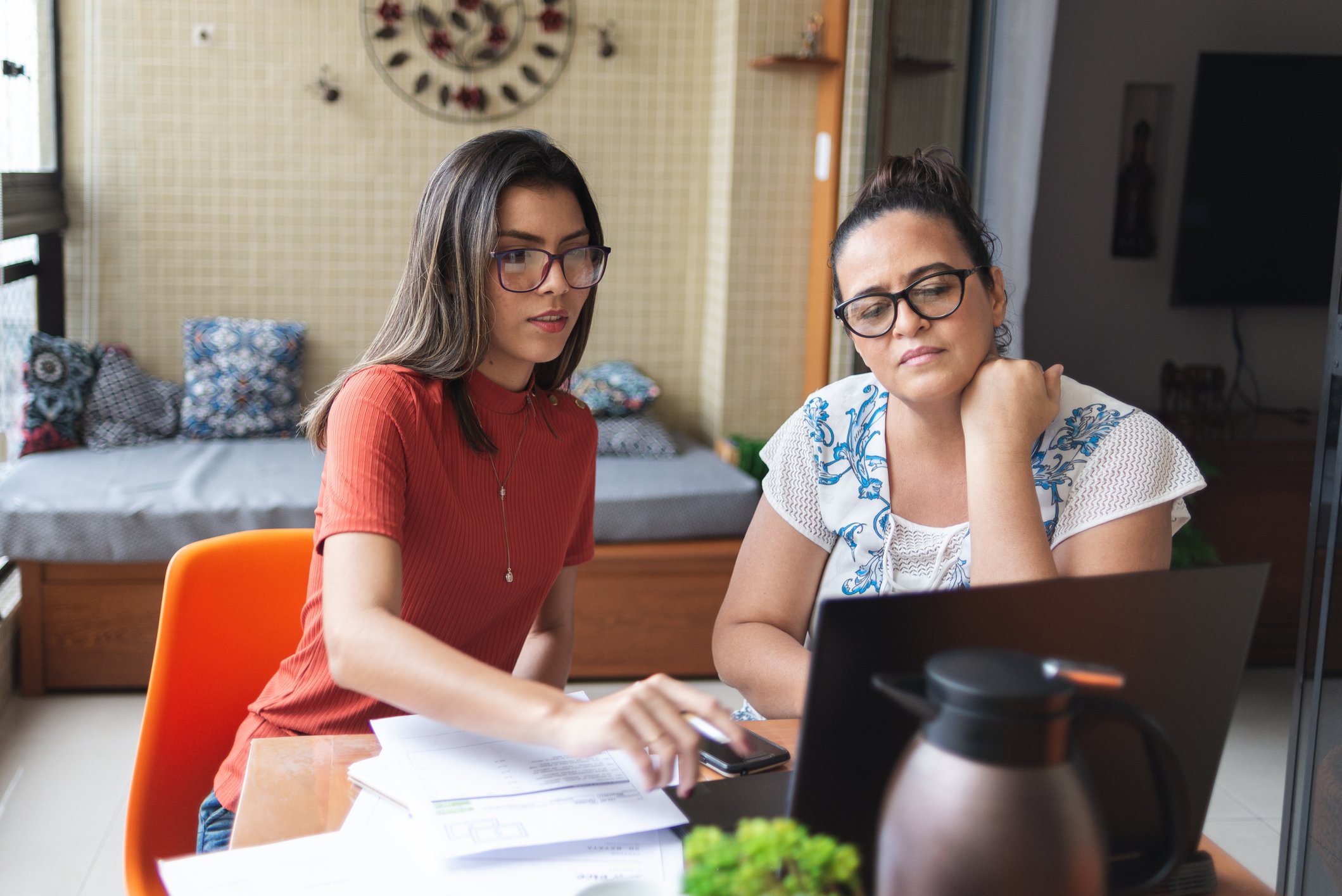 Two people looking at their taxes in front of a laptop.