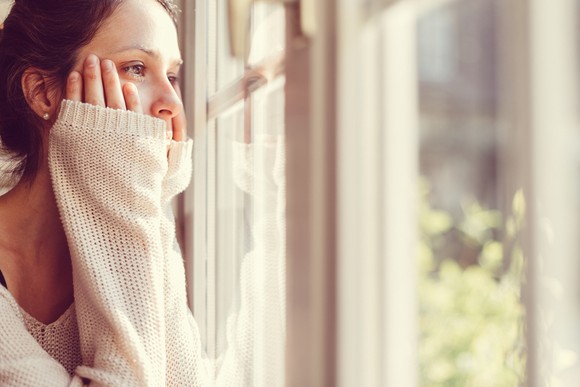 A person stares out of a home's window.