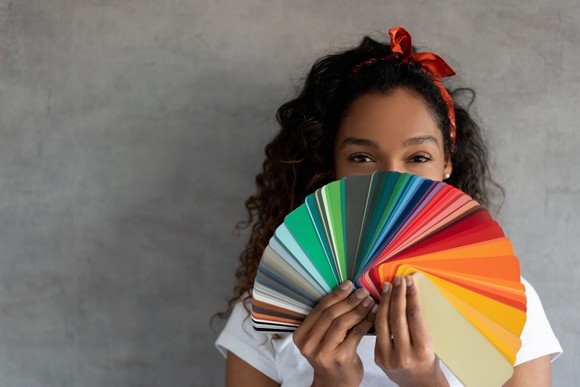 A young person looking over a palette resembling a fan of colors.