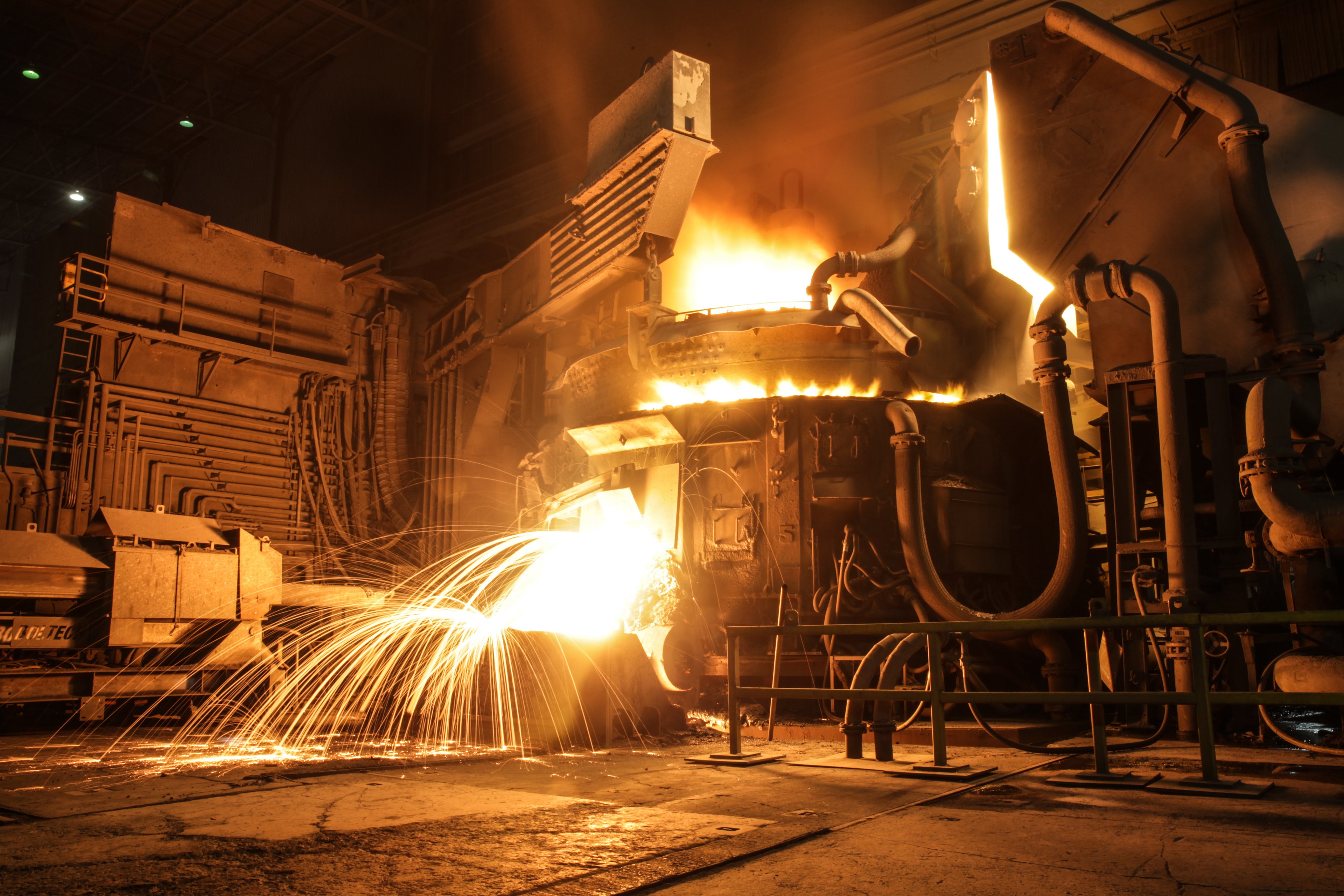 electric arc furnace (EAF) melting scrap into steel with sparks. 