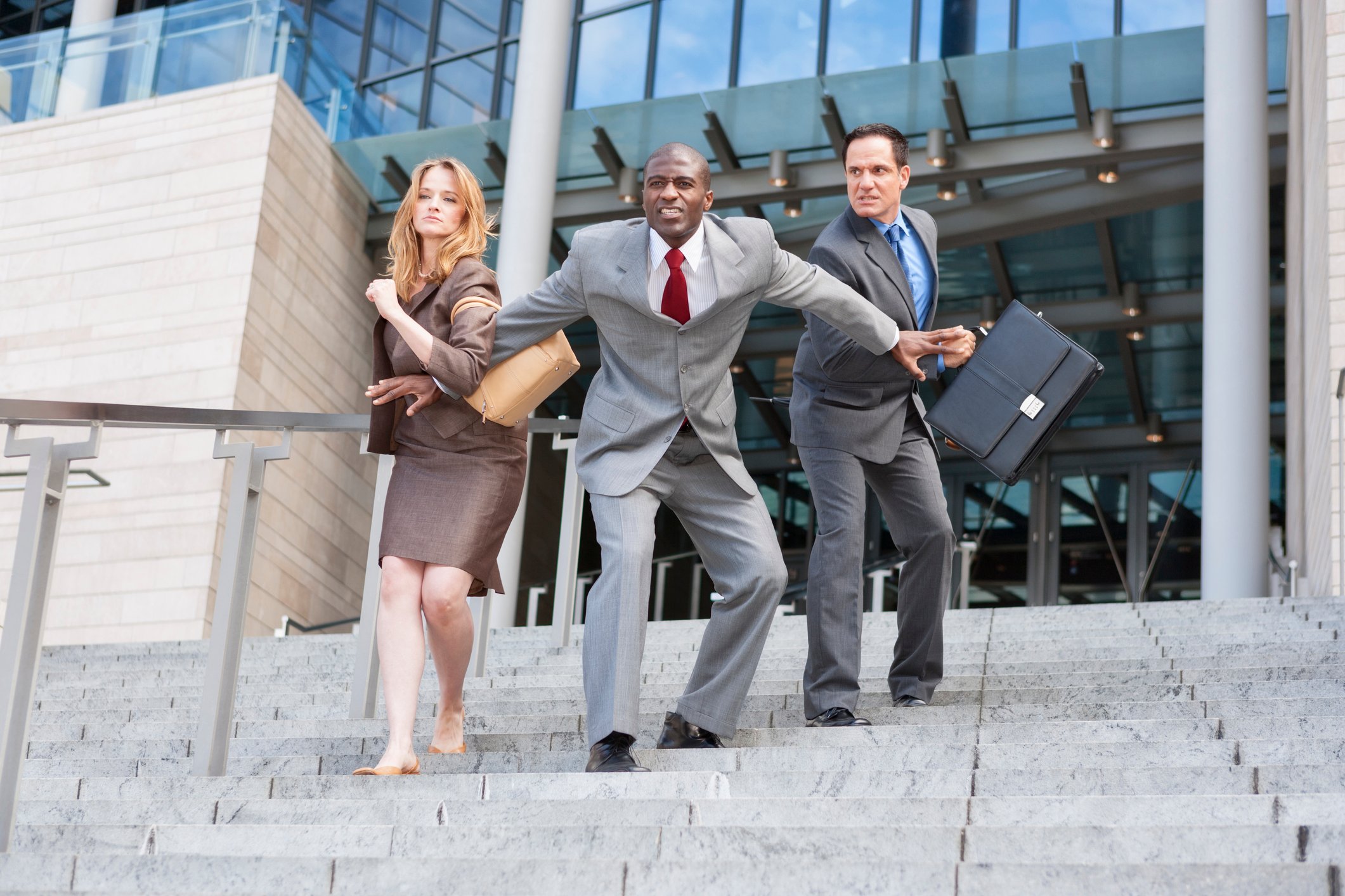 Person holding two other people back.