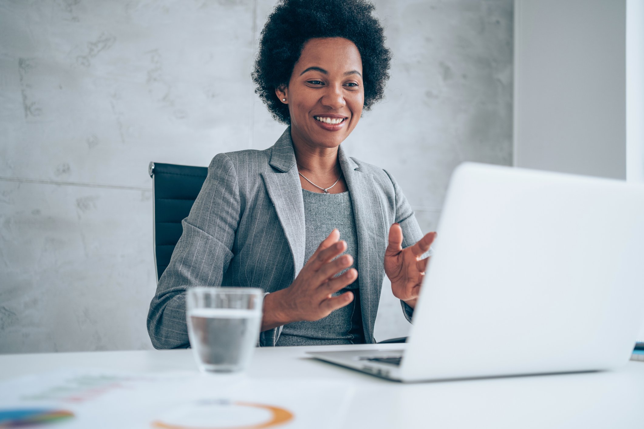 A business person at their desk looking at their laptop, smiling. 