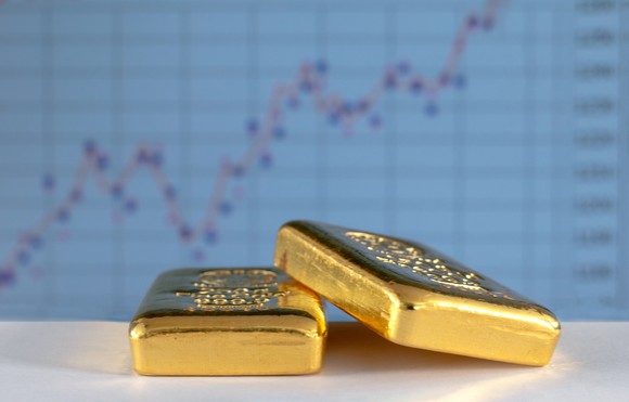 Gold bars in front of a stock chart. 