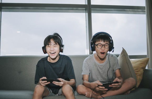 Two children play a video game while sitting on a couch.