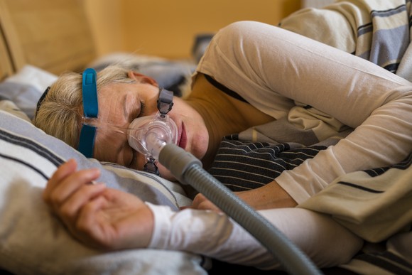 A patient wearing a sleep apnea mask in bed.