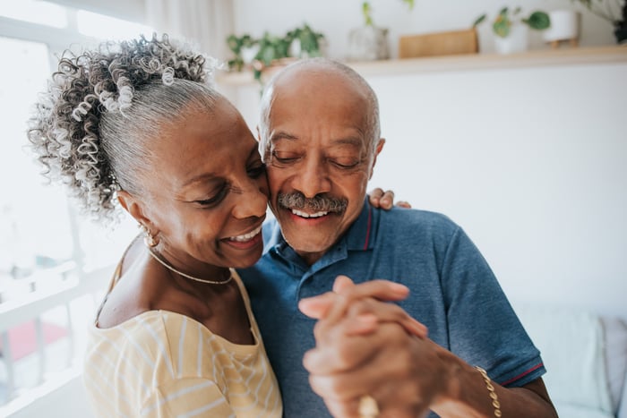 Two older people dancing together and smiling.