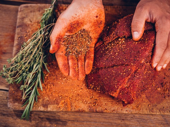 Person rubbing spices on a piece of meat.