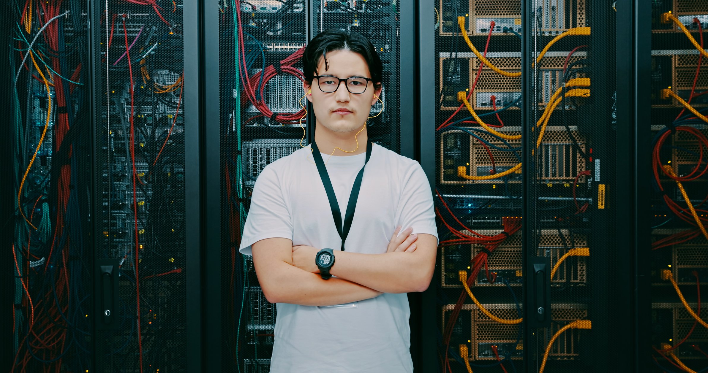Software engineer posing in front of a rack of servers.