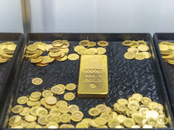 Gold coins surround a gold bar on a tray. 
