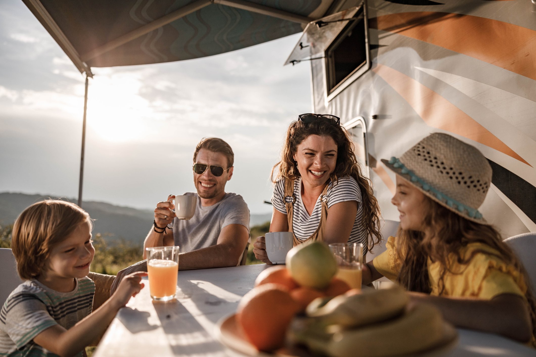 A family enjoys a meal outside their RV camper.