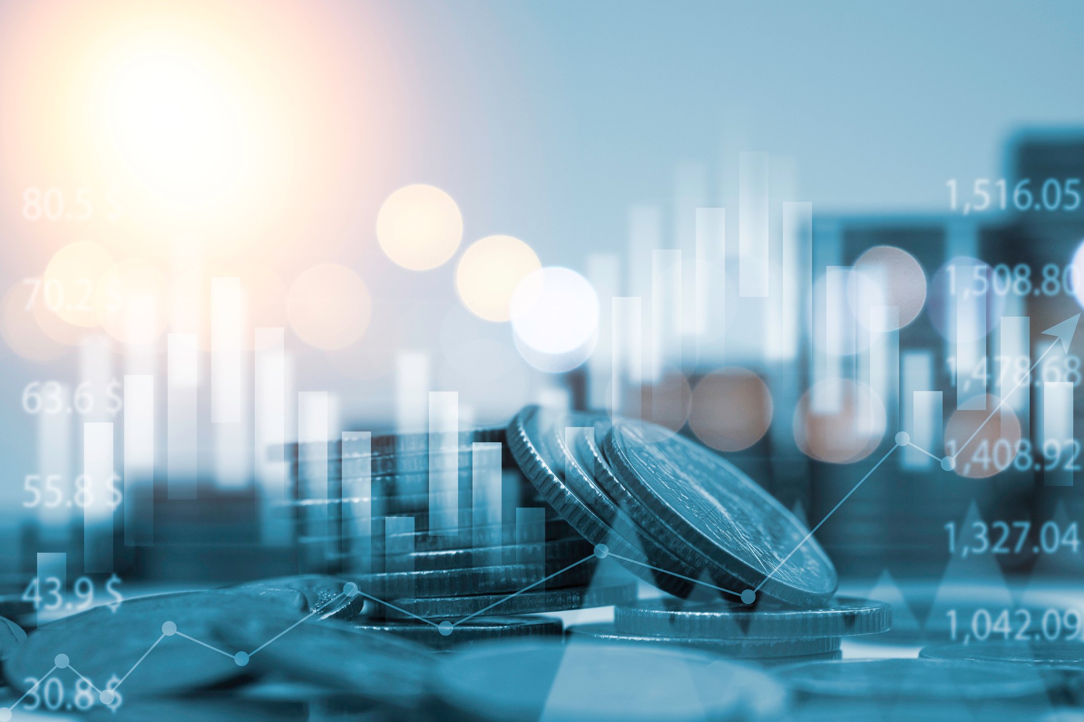 A pile of coins with graphs and numbers in the background.