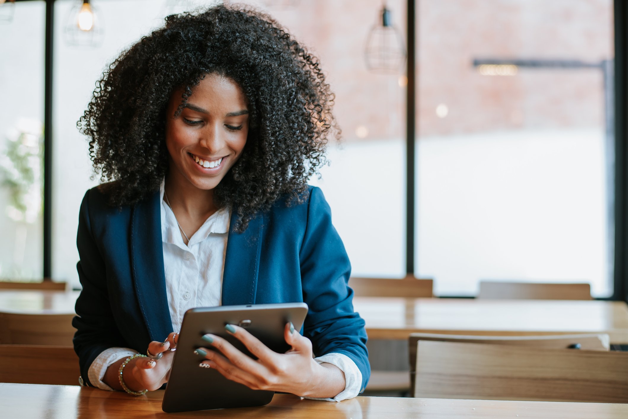 A person smiling and looking at a tablet.