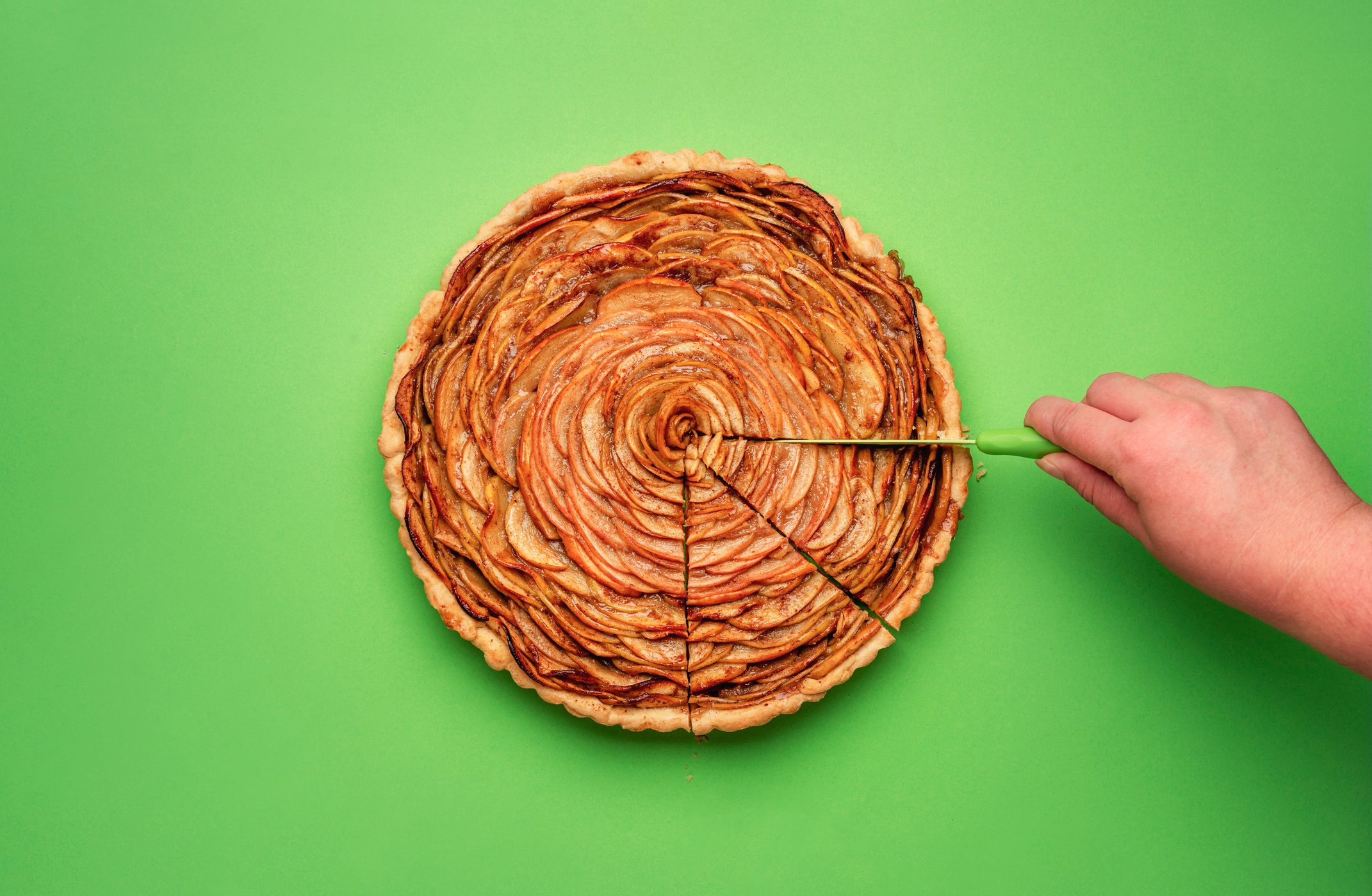 Person slicing an apple pie.