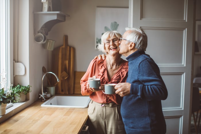 Two people standing in a kitchen and smiling.