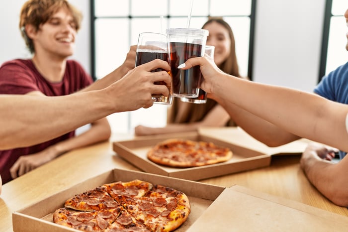 A group of people enjoy cola with pizza.