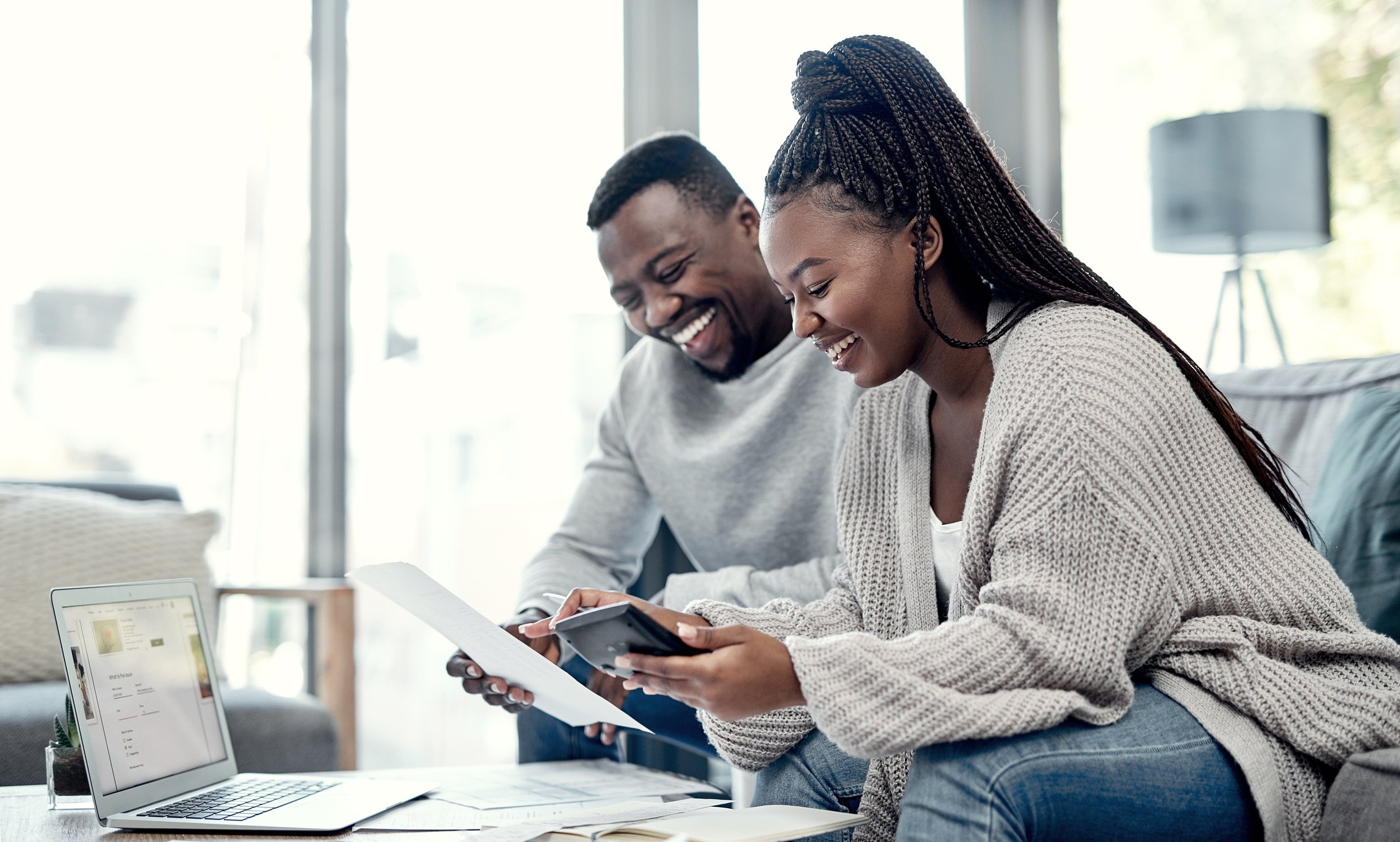 Two people with laptop and phone, reviewing documents.