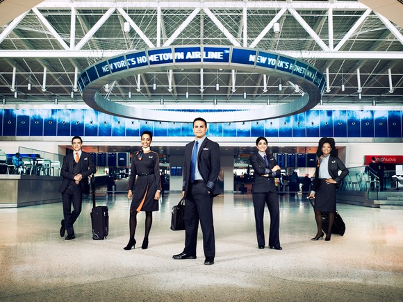 A JetBlue flight crew posing for a photo in an airline terminal.