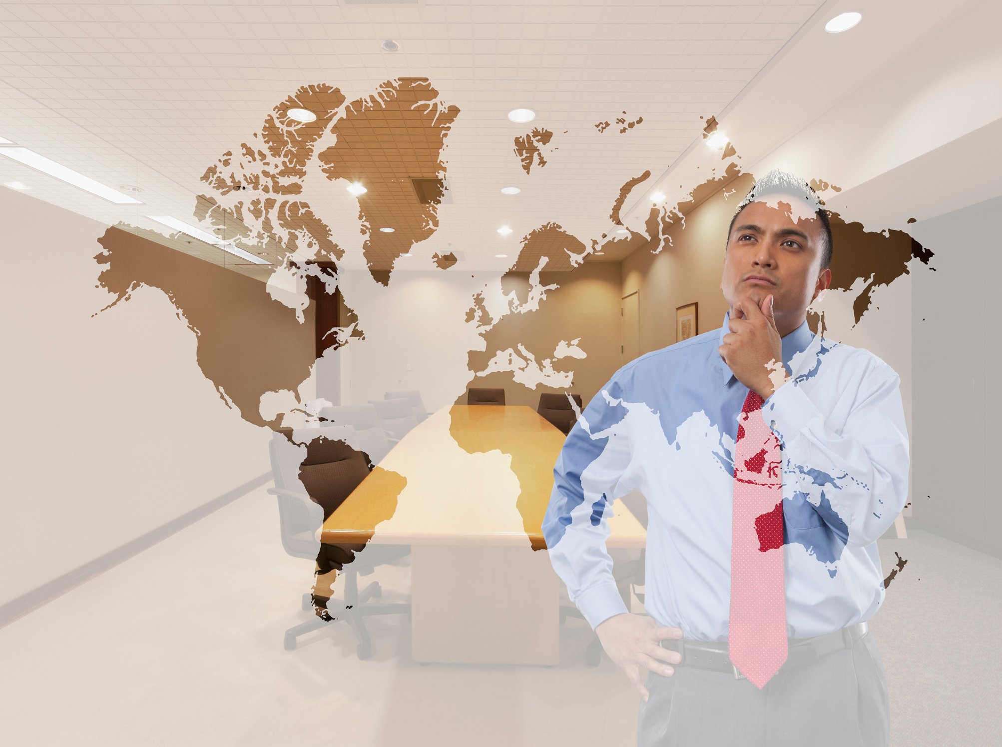 A businessman looks at a map of the world as he touches his chin thoughtfully.