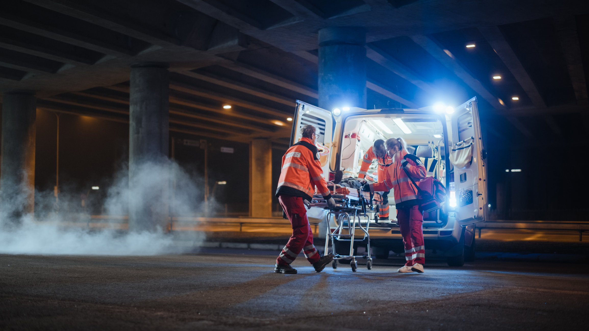 Paramedics loading a patient into an ambulance.