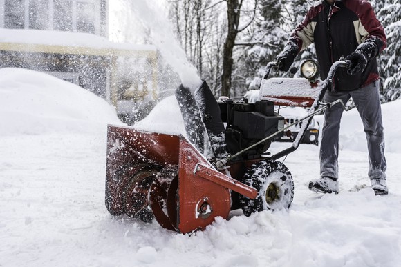 A person operating a snow blower. 