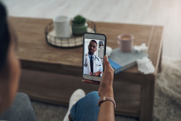 Person speaking with a doctor over a video call on a smartphone.