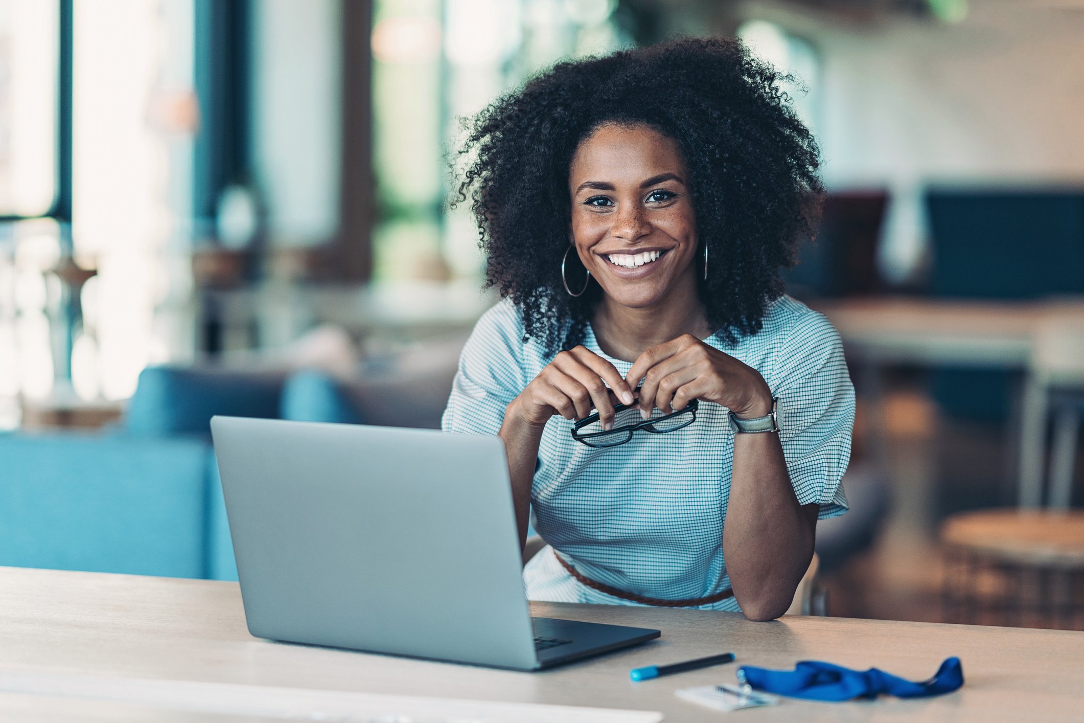 Person smiling at table in front of computer.
