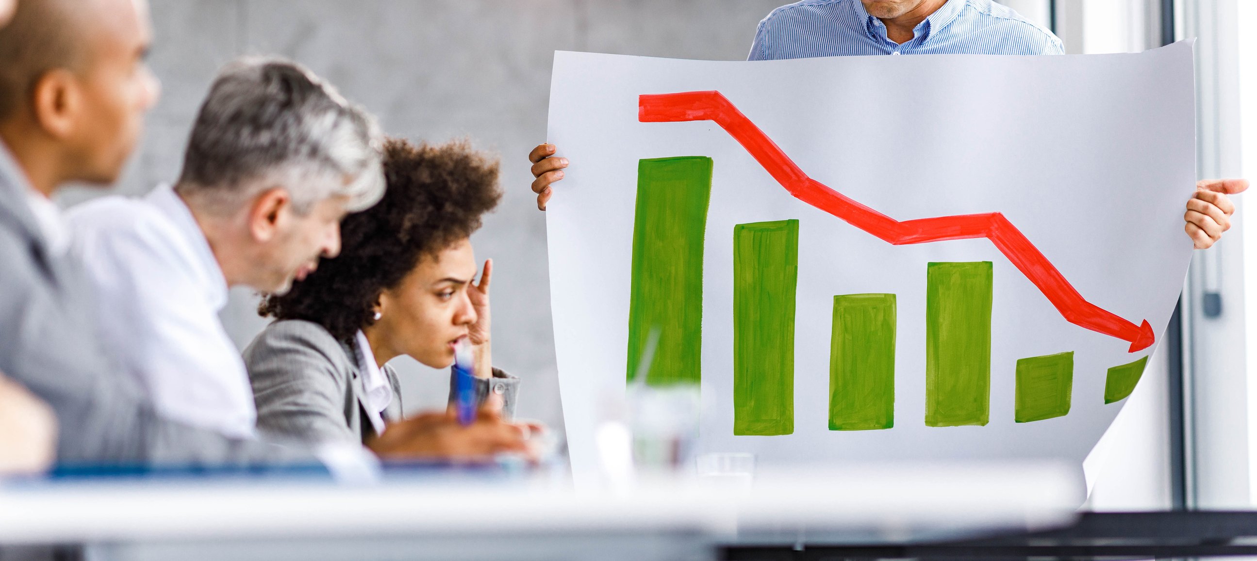 Employees look a a declining chart during a meeting.