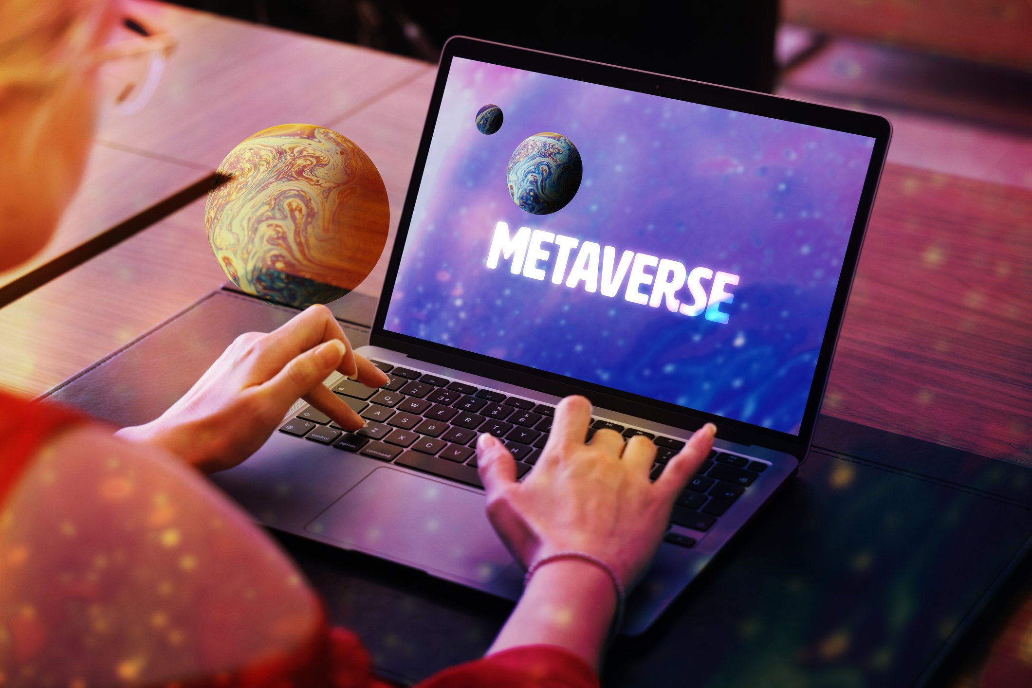 A person using a laptop, and the screen says the word Metaverse.