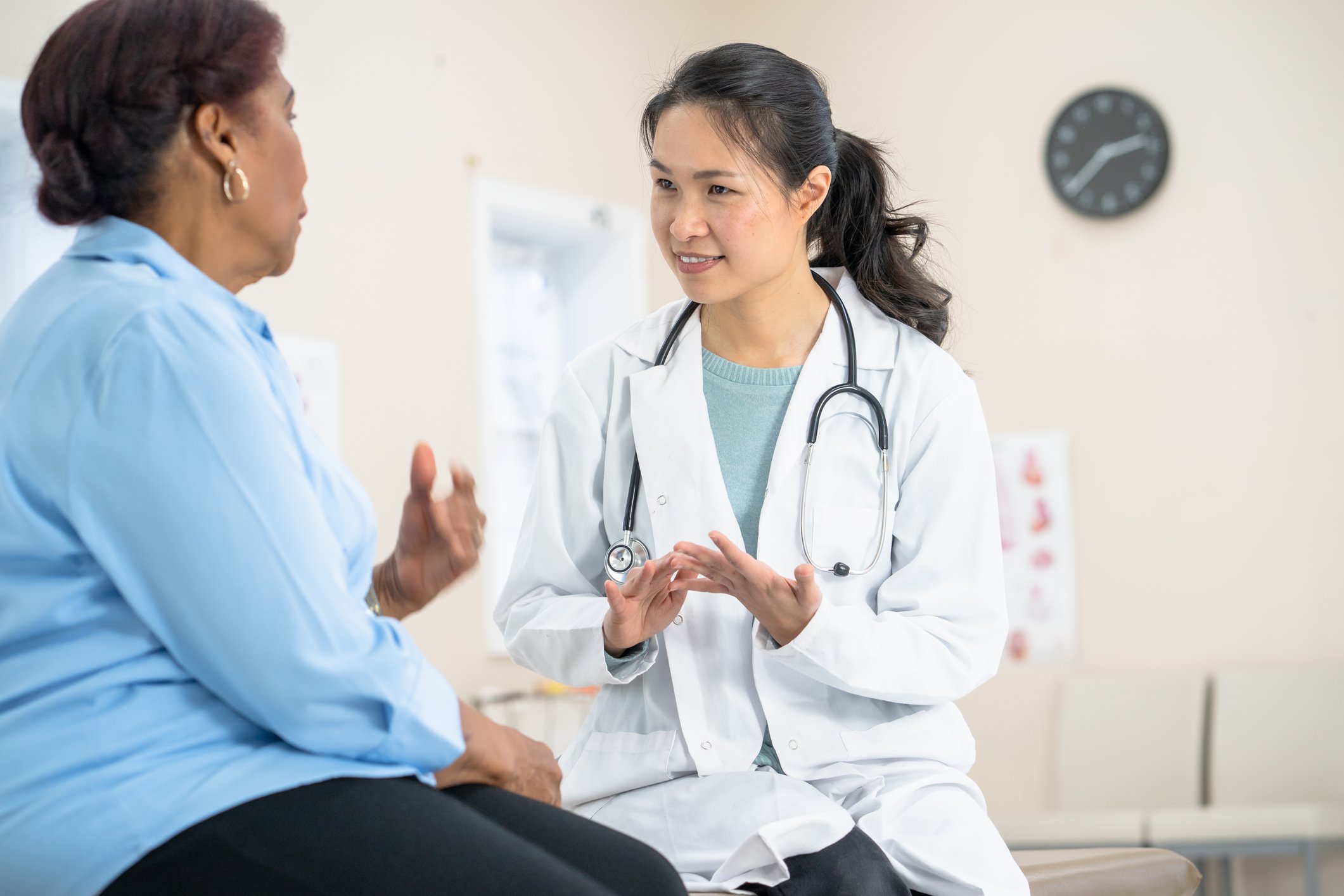 A doctor speaks to a patient in an examining room.