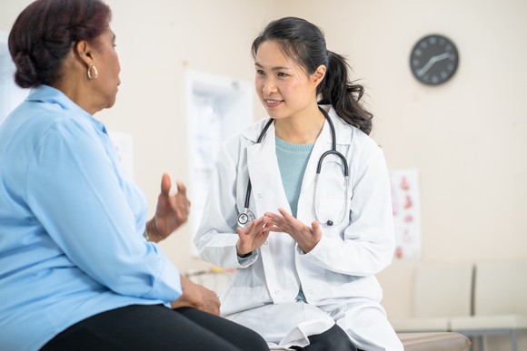A doctor speaks to a patient in an examining room.