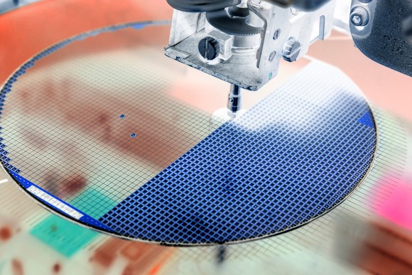 A machine etches semiconductors  onto a circular silicon wafer. 