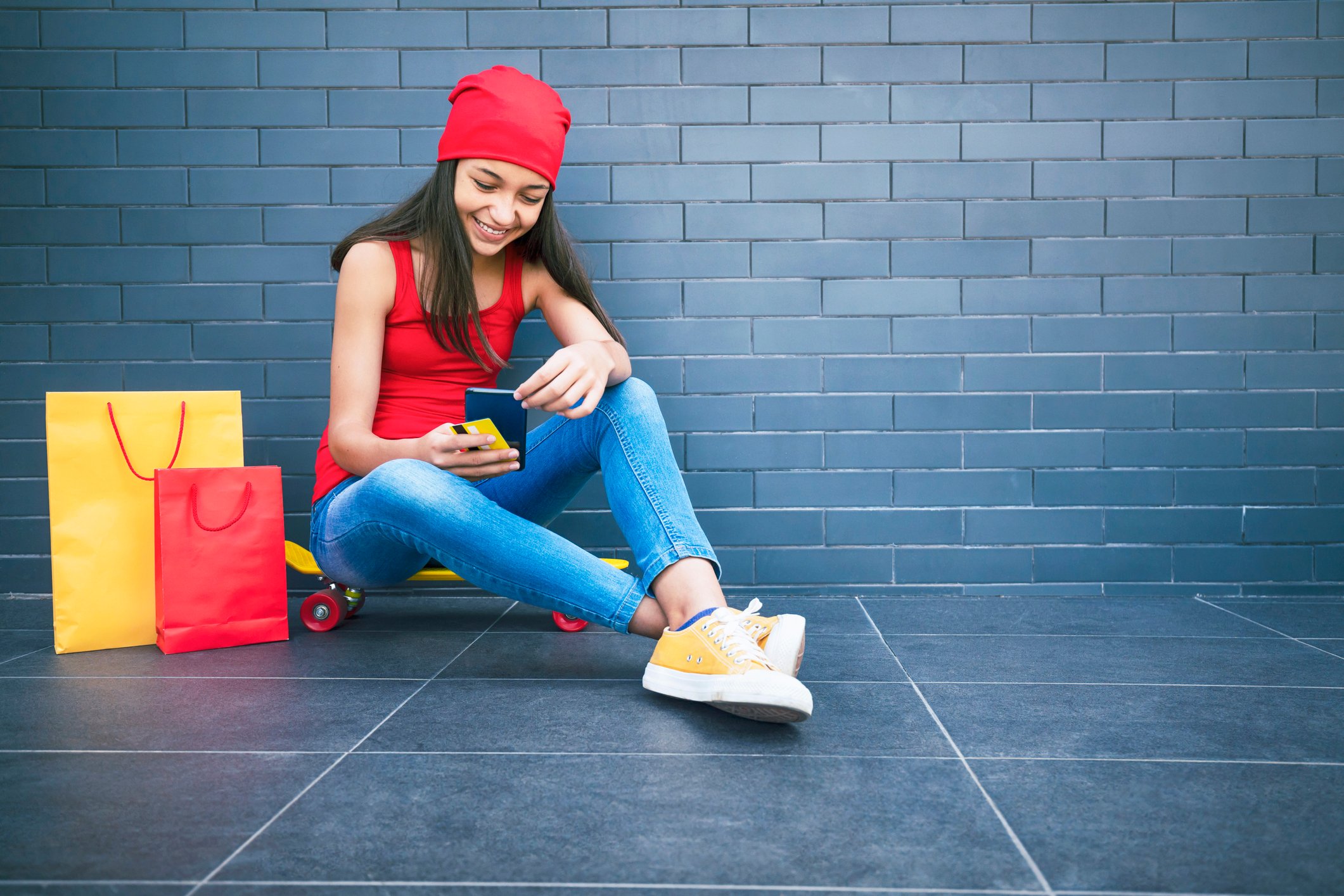 Shopper holding cellphone while sitting next to shopping bags.
