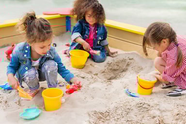 Kids play with shovels and pails in a sandbox.