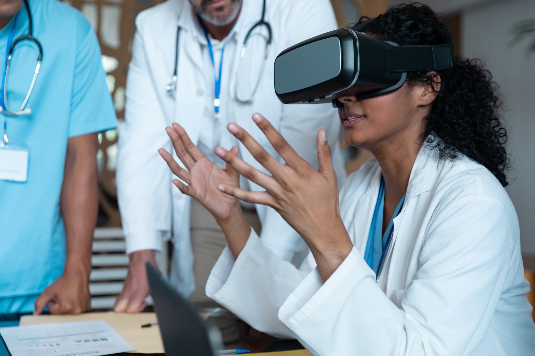 A doctor investigates a medical issue while wearing VR glasses as colleagues look on. 