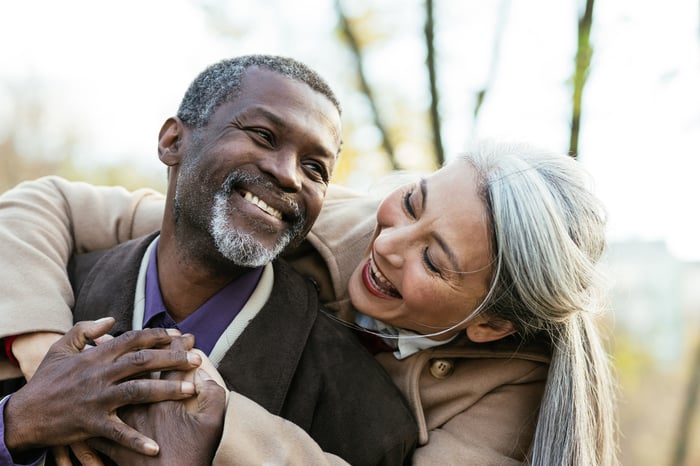 A couple is embracing and smiling broadly.