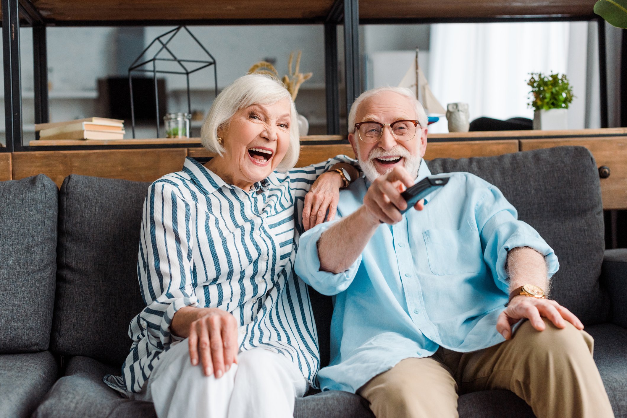 Two people sitting on a couch. One person is holding a remote control.