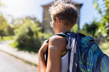 teenager walks with backpack and bandaid on arm