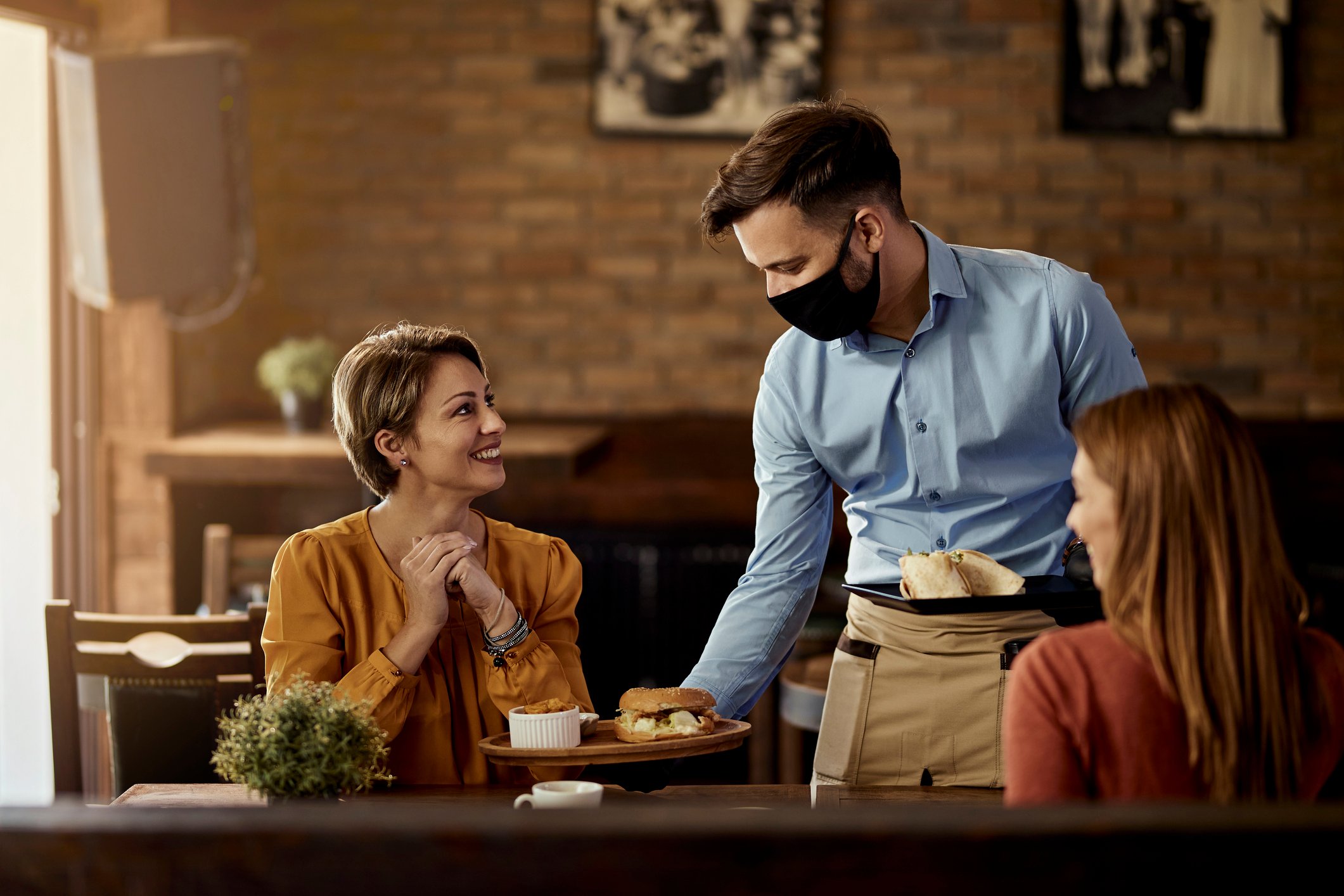 A server hands food to customers at a restaurant.