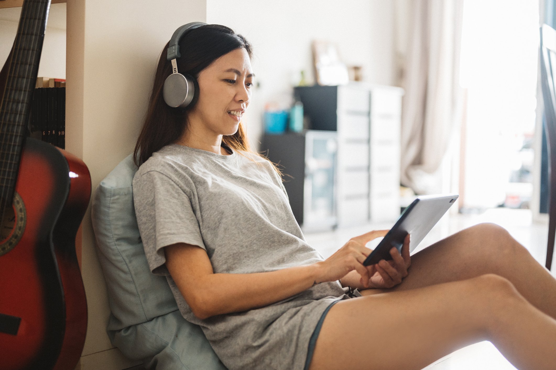 A student wearing headphones watches a program on a tablet.