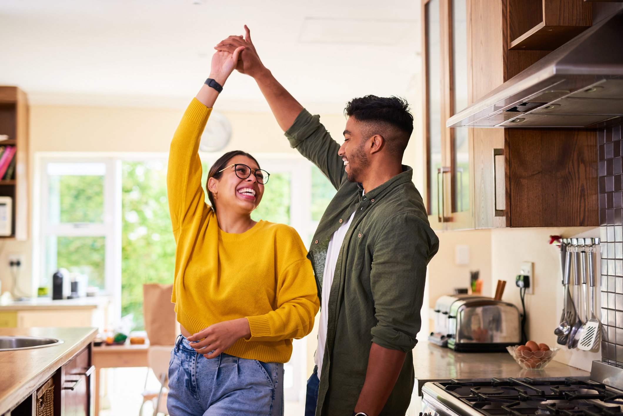 Shot of a young couple dancing together in their kitchen.