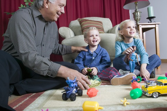 Two young children playing with toys as an adult watches.