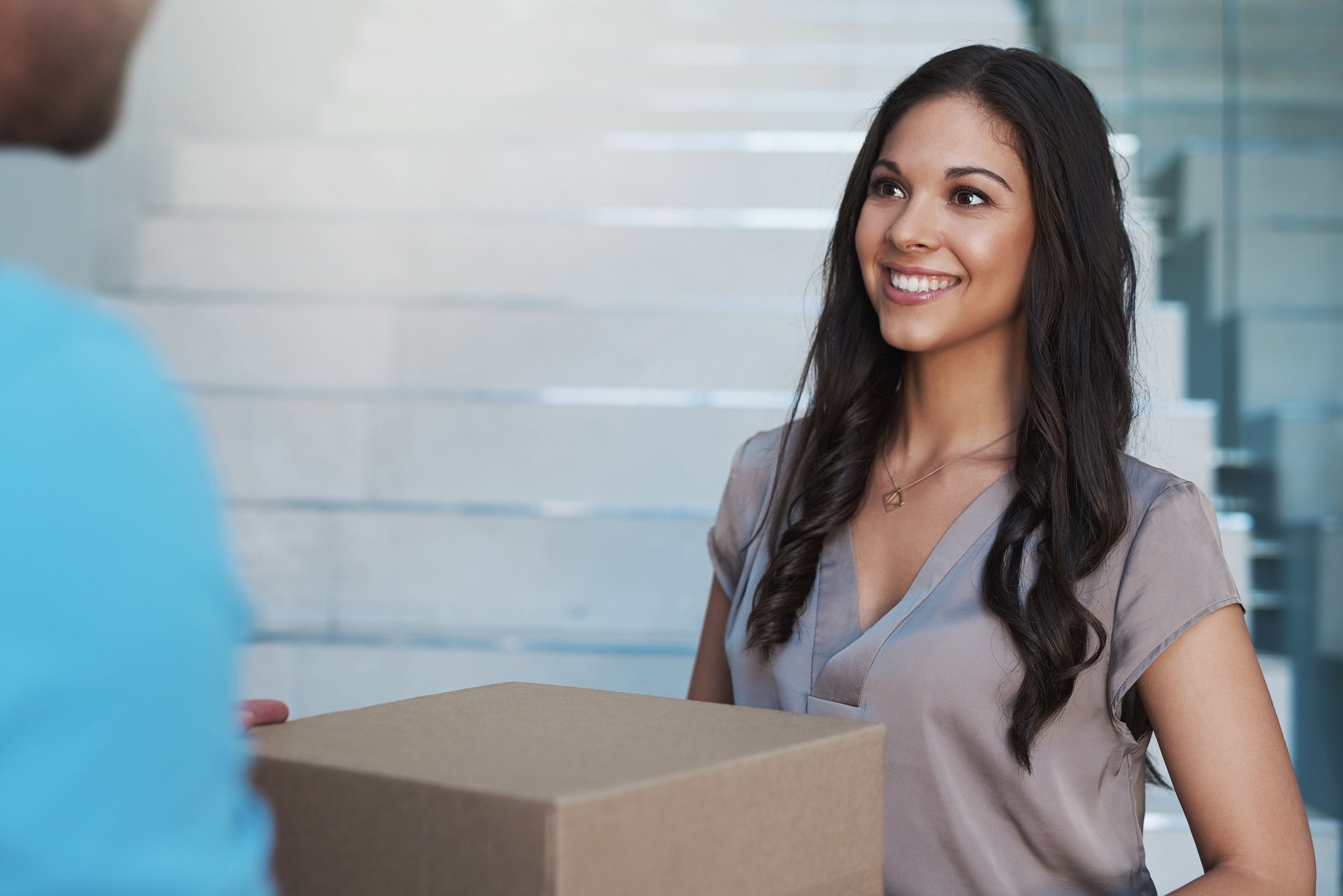 Woman smiles receiving a package. 