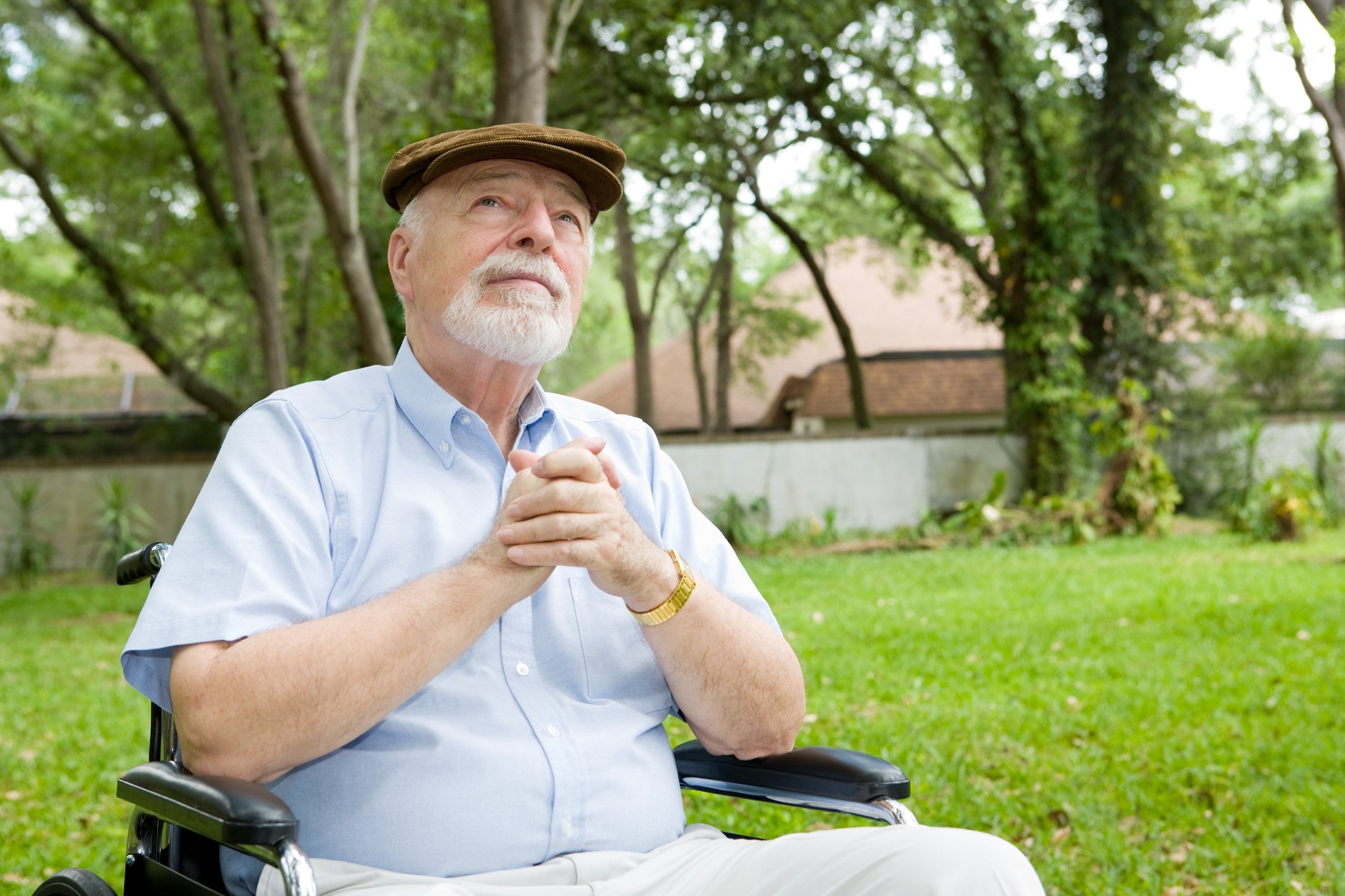 An older person is outside, looking up at the sky.