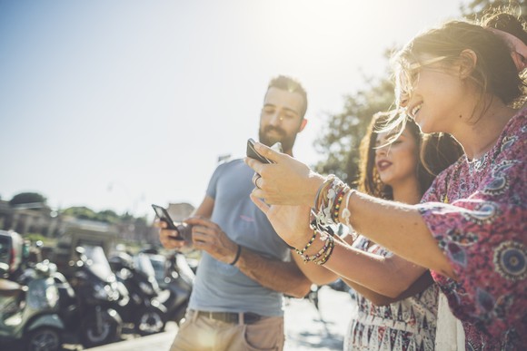 A group of friends takes and shares photos with their smartphones.